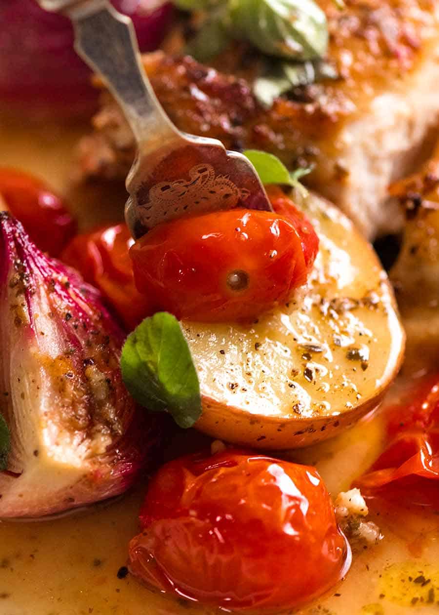 Close up of fork picking up tomato and potato from Mediterranean Chicken and Potato Bake