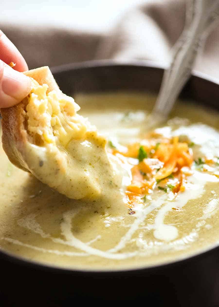 Warm crusty bread being dunked into creamy Easy Broccoli Soup