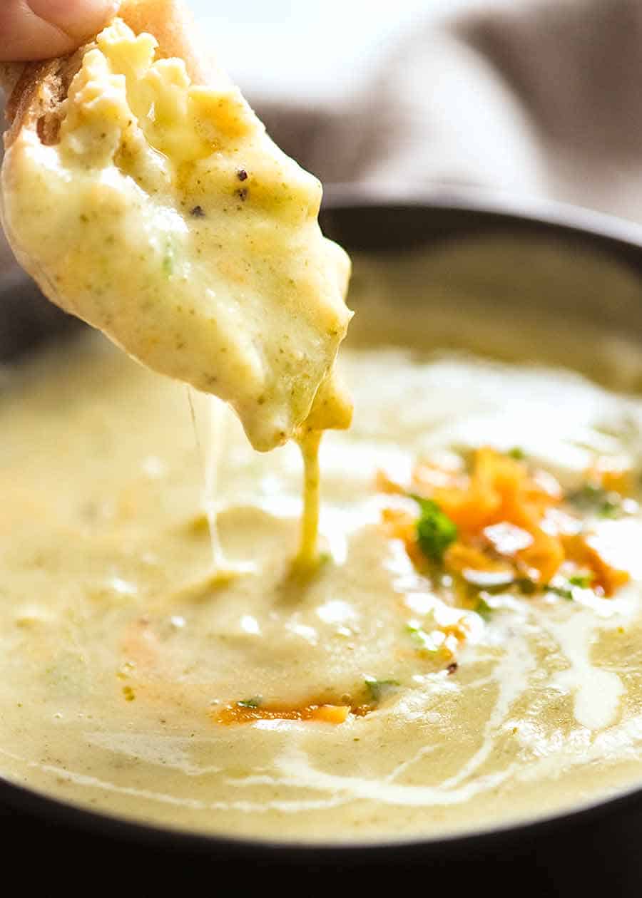 Bread being dunked into Broccoli Cheese Soup with fabulous cheese pull!