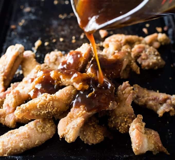 Pouring sauce over Chinese Honey Sesame Chicken