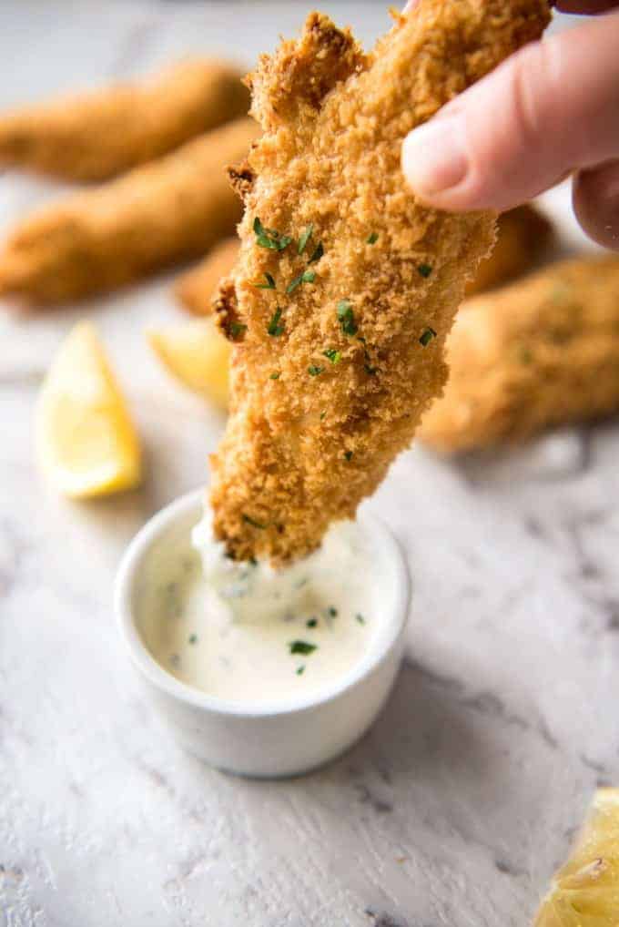 Oven Fried Chicken Tender being dipped into a small dish of ranch dipping sauce.