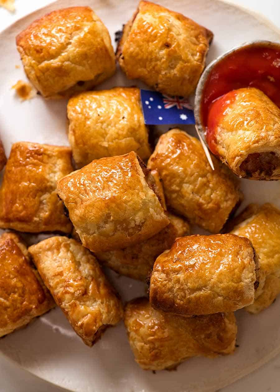 Overhead photo of pile of Sausage Rolls with tomato sauce