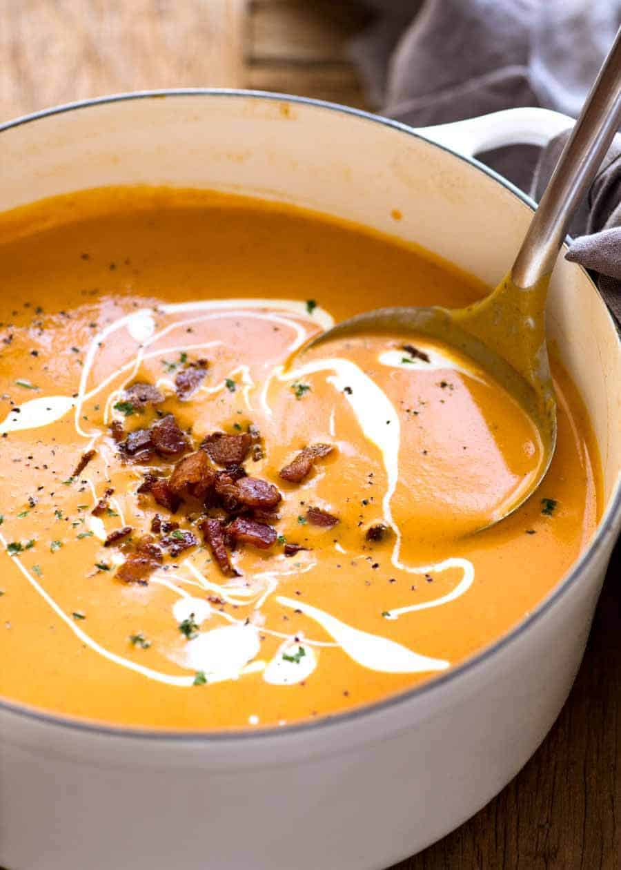 Thick and creamy Carrot Soup in a white cast iron pot, ready for serving.