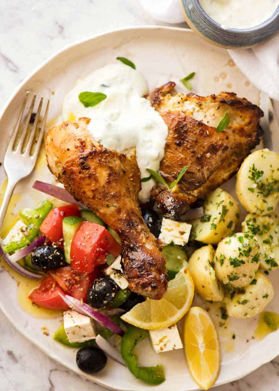 Baked Greek Chicken on a plate with Greek Salad and Lemon Potatoes