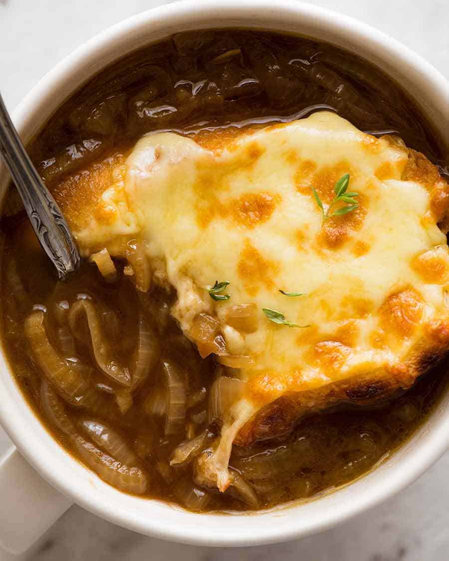 Close up overhead photo of French Onion Soup in a white bowl with a spoon