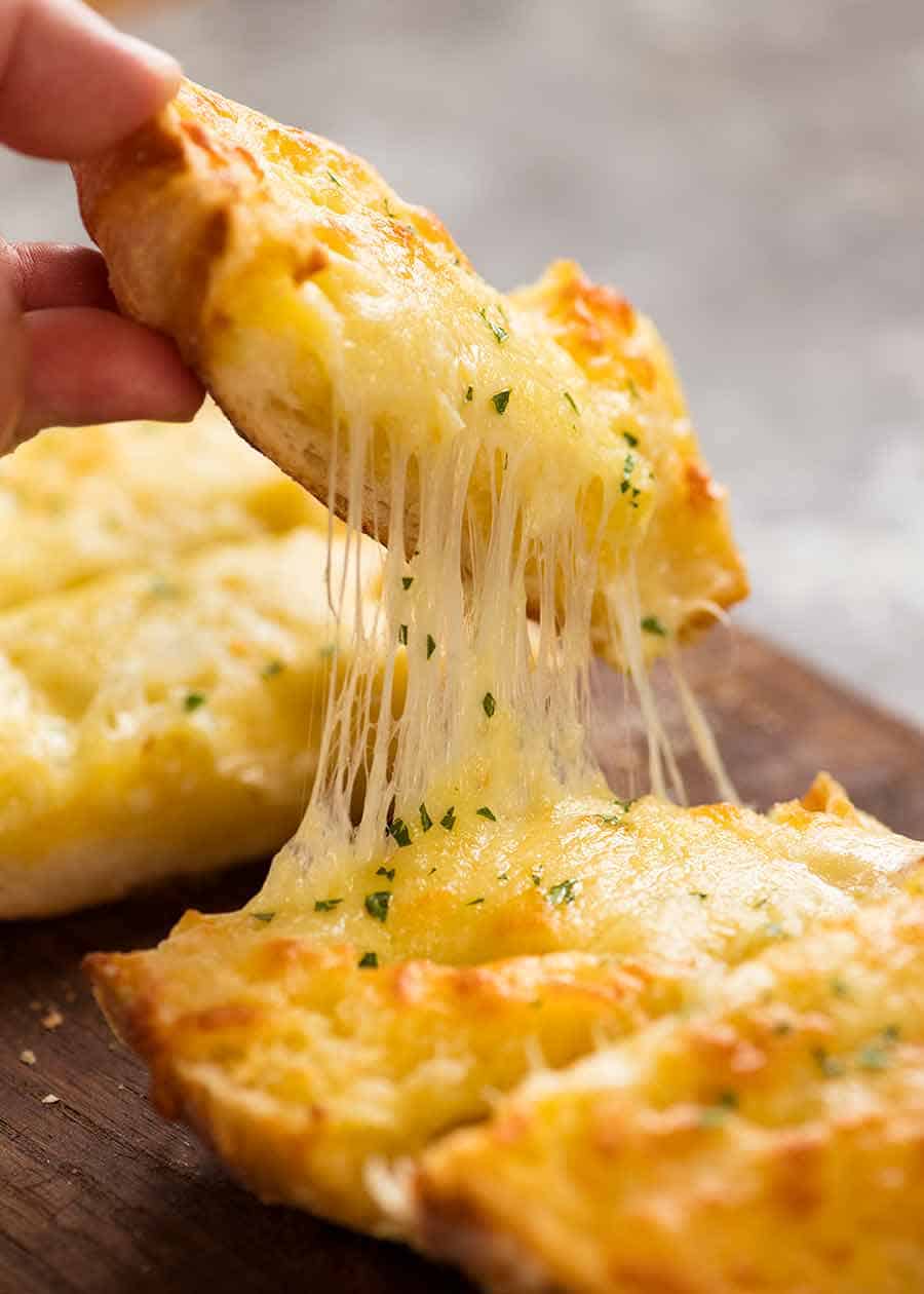 Hand pulling up a piece of Quick Cheesy Garlic Bread with stretchy cheese