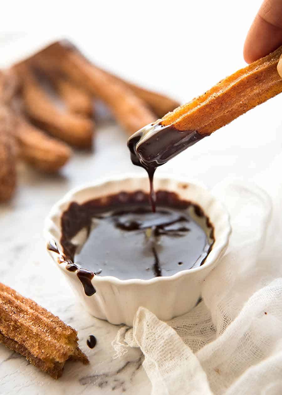 Churros being dipped into hot chocolate 