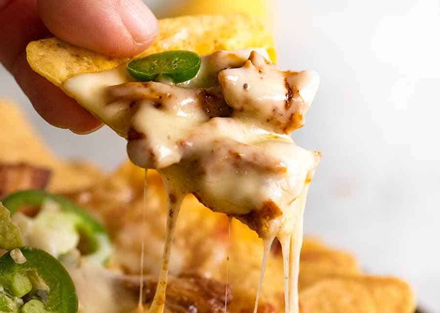 Chicken Nachos cheese pull - hand holding corn chip